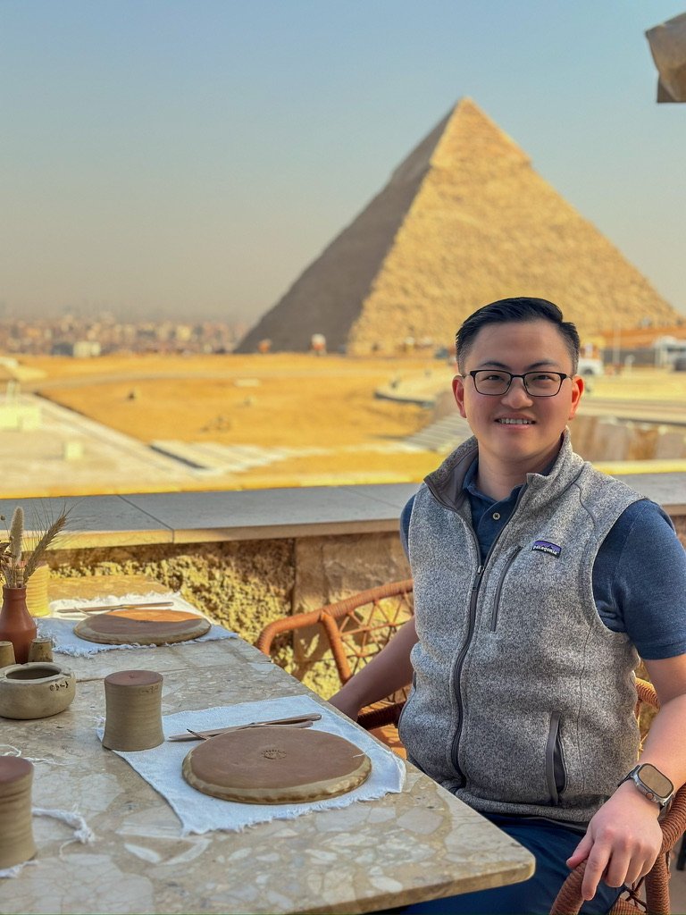 Johnew at a table on Khufu's terrace with the Great Pyramid behind