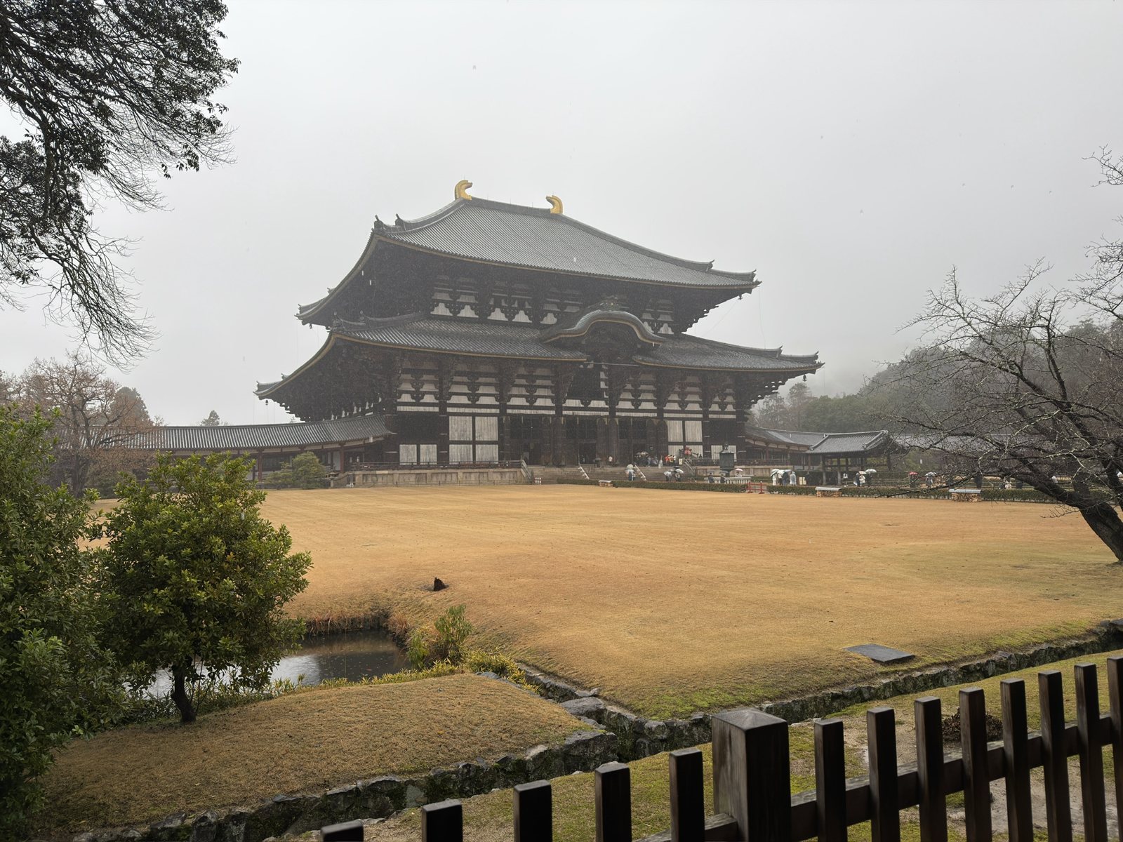 The Great Buddha Hall of Tōdai-ji in rain and mist, across a lawn