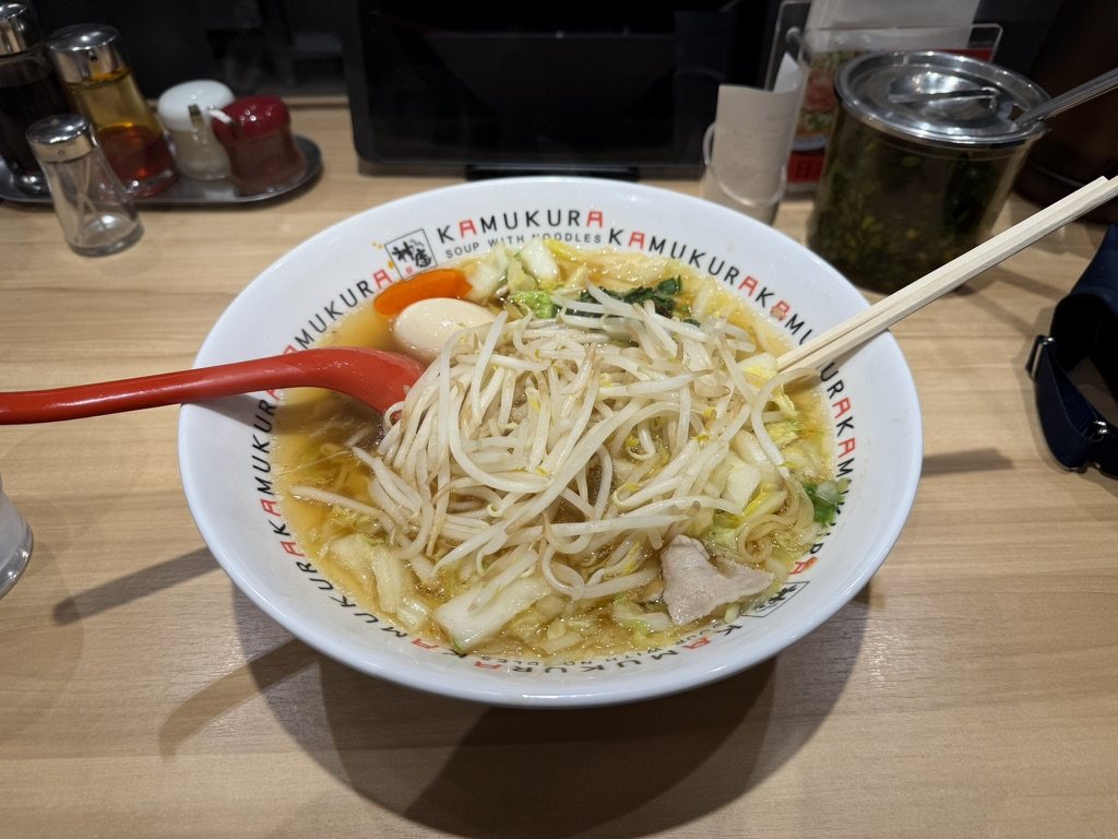 A bowl of ramen with cabbage, bean sprouts, and an egg in a Kamukura bowl