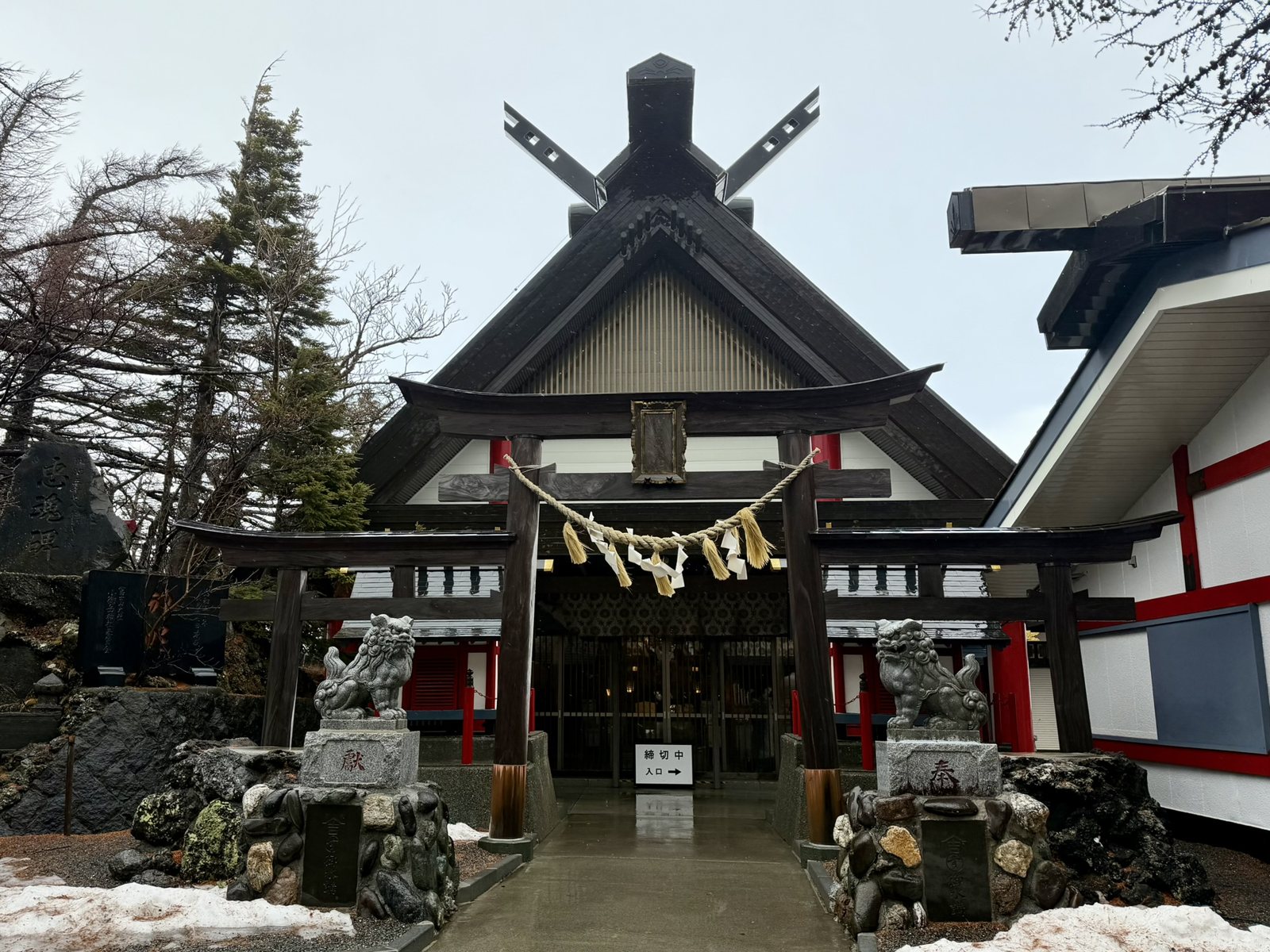 Komitake Shrine at the Mt Fuji fifth station, with a torii, a sacred rope, and guardian lion-dogs, and snow on the ground