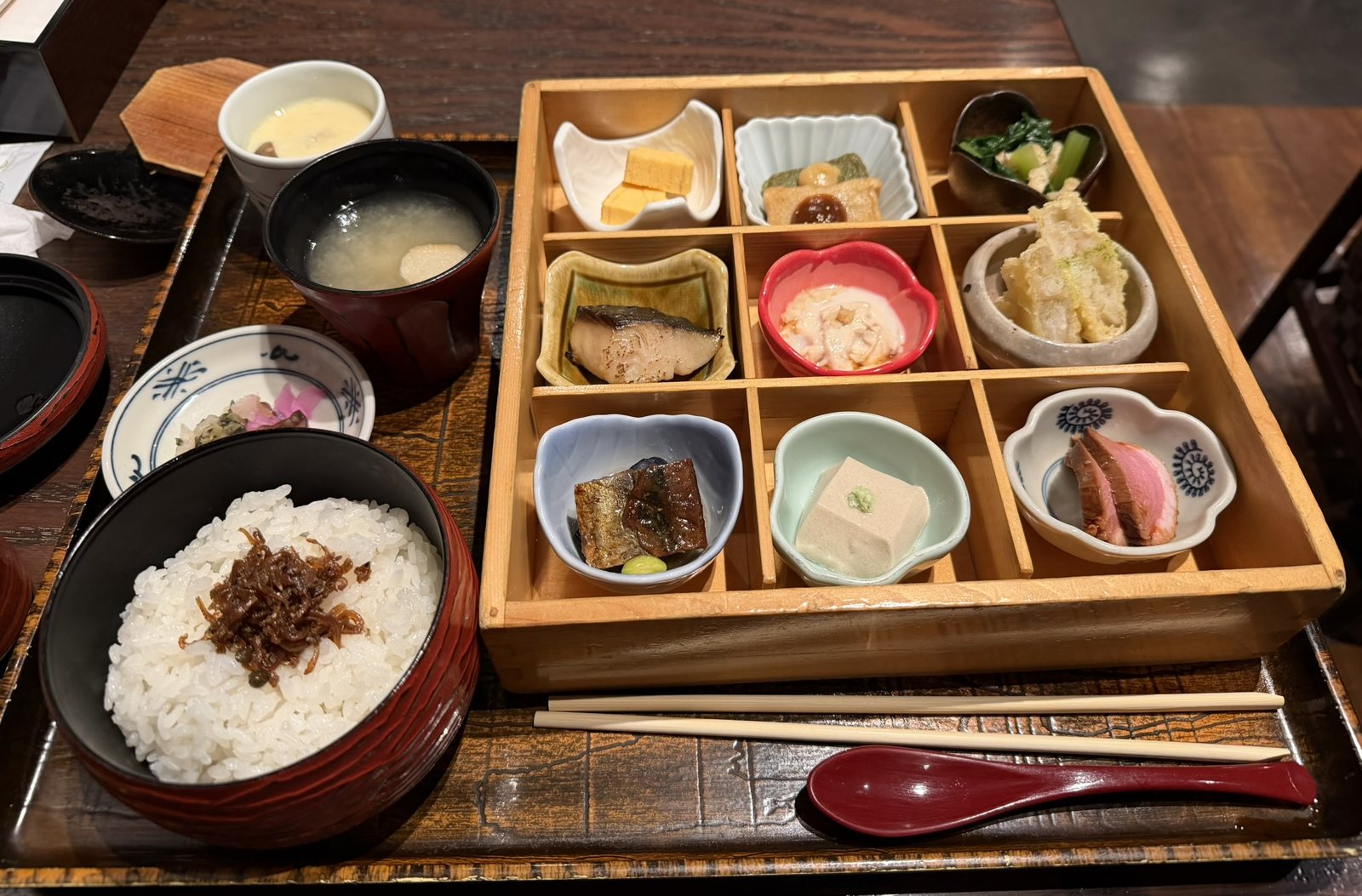 A lunch tray with rice, miso soup, and a nine-compartment box of small Kyoto dishes