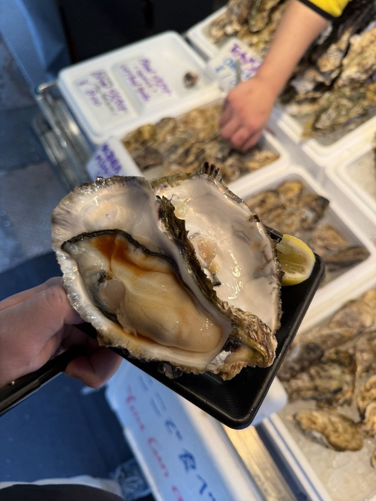 A large raw oyster held up at a stall in the Tsukiji outer market