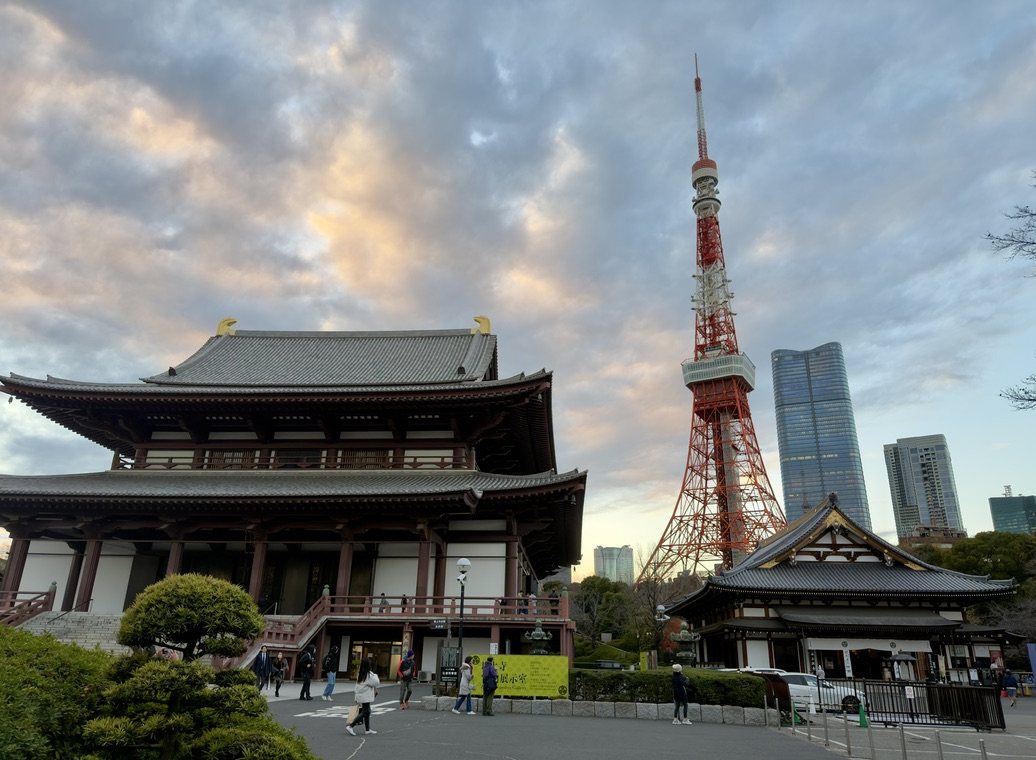 The main hall of Zōjō-ji with Tokyo Tower rising behind it at dusk