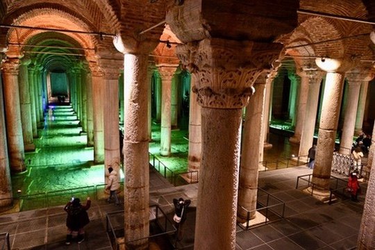 Rows of lit marble columns rising from shallow water in the Basilica Cistern