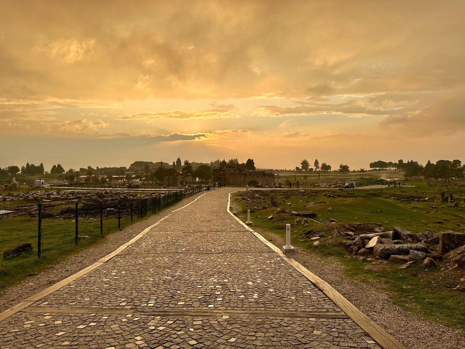 A paved Roman street at Hierapolis under an orange evening sky