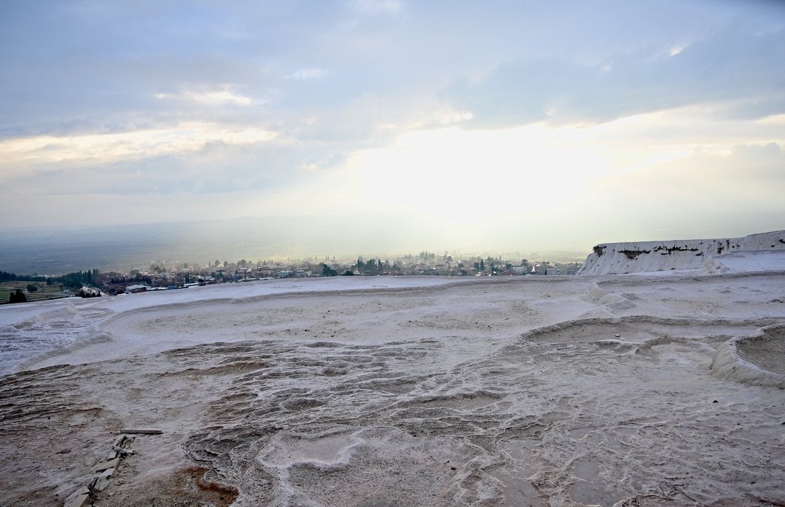 The white crust of the travertines under a hazy late-afternoon sky