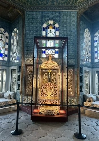 A gilded throne in a glass case inside a tiled pavilion at Topkapı