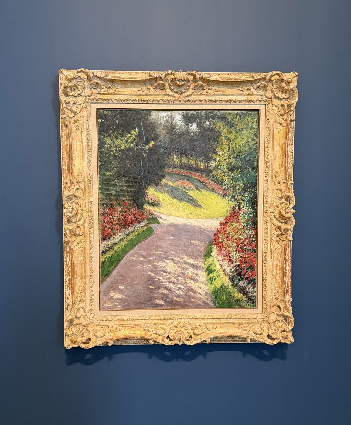 Caillebotte, a sunlit garden path between red flower beds